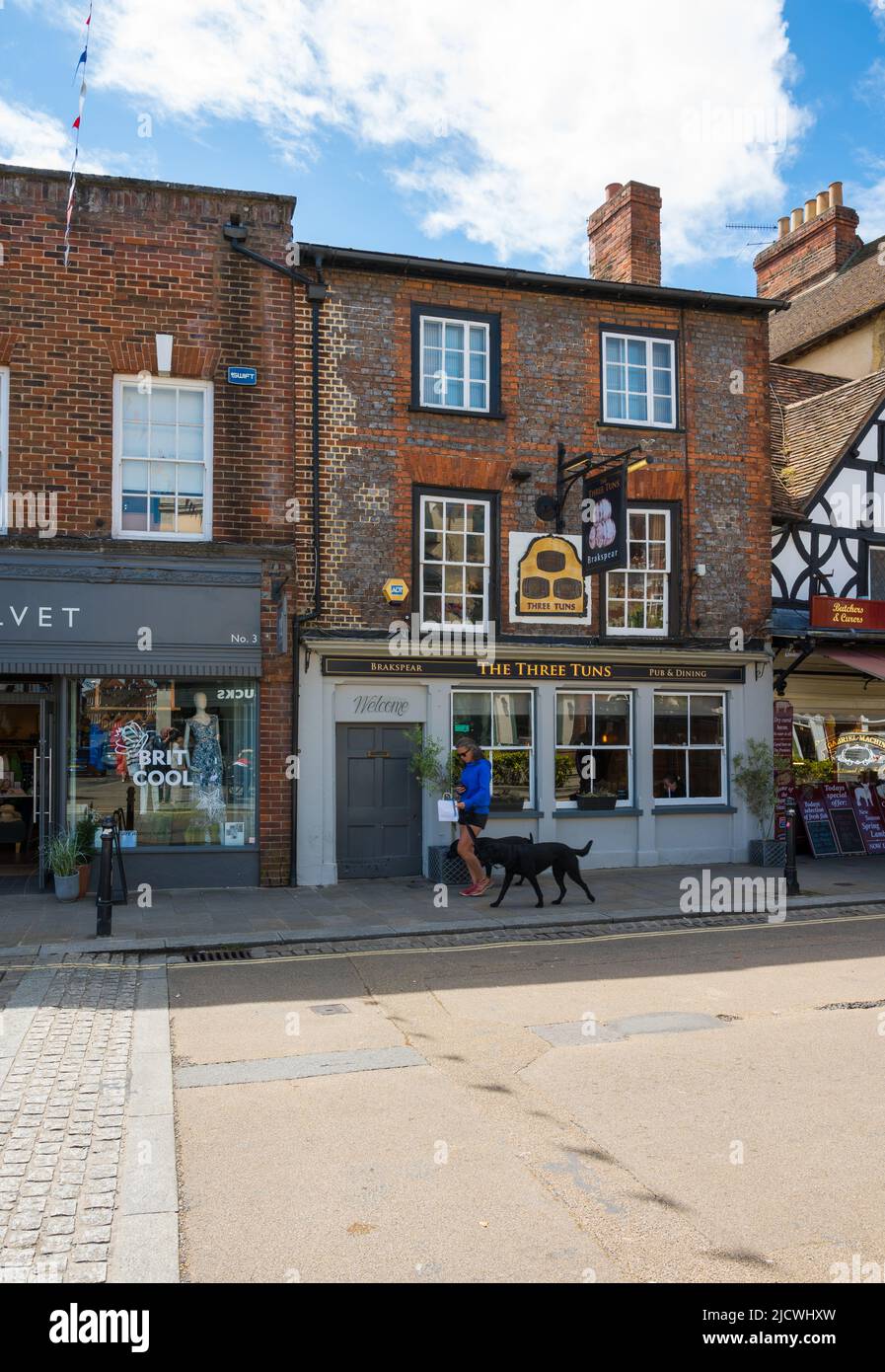 The Three Tuns Pub. Eine Frau mit zwei schwarzen Labrador-Hunden auf der Leine geht vorbei. Market Place, Henley on Thames, Oxfordshire, England, Großbritannien. Stockfoto