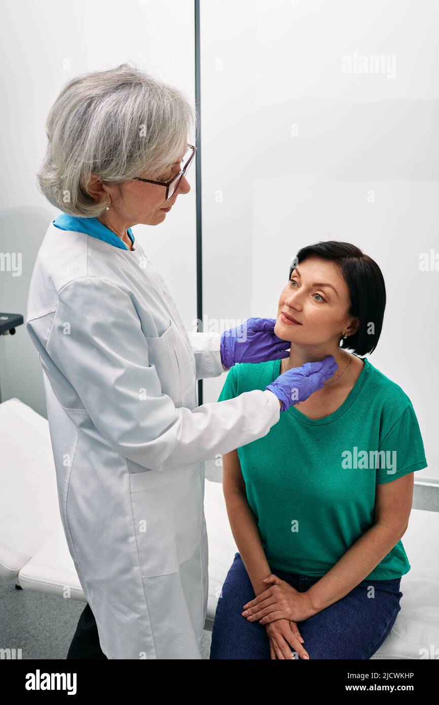 Die Endokrinologin tastet den Hals der Frau zur Diagnose von Schilddrüsenerkrankungen. Untersuchung und Behandlung der Schilddrüse Stockfoto