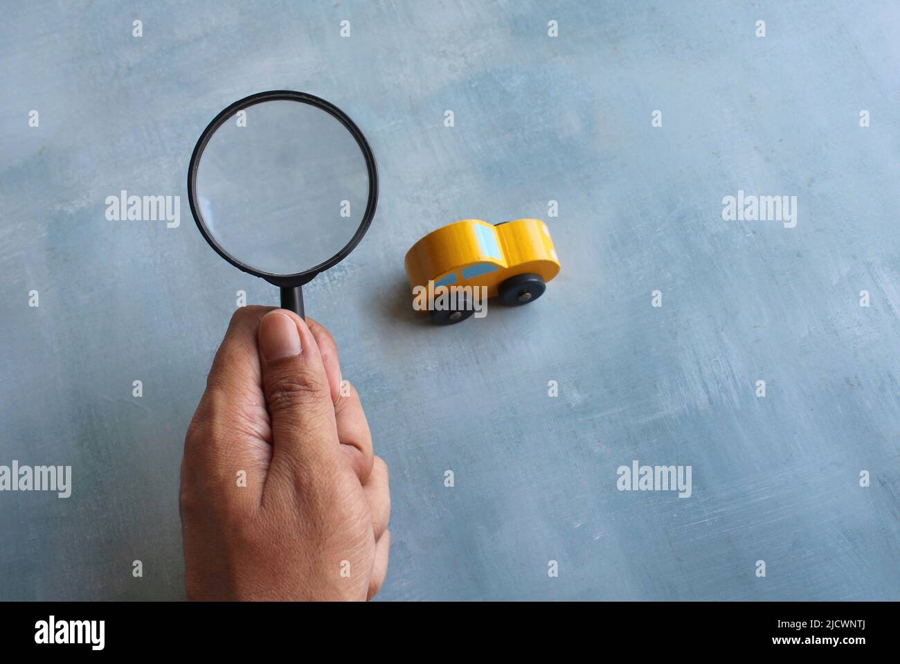 Hand hält Lupe und Spielzeug Auto. Auto Inspektion, Suche, auf der Suche nach Auto-Konzept. Stockfoto