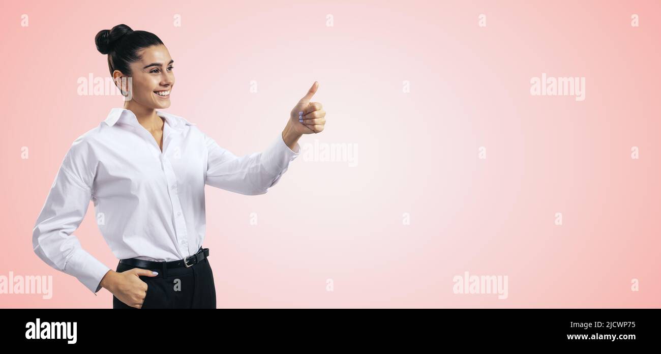 Wie Konzept mit glücklichen Mädchen in weißem Hemd halten Daumen nach oben auf hellrosa Wand Hintergrund mit leerem Platz für Sie Text, mockup Stockfoto