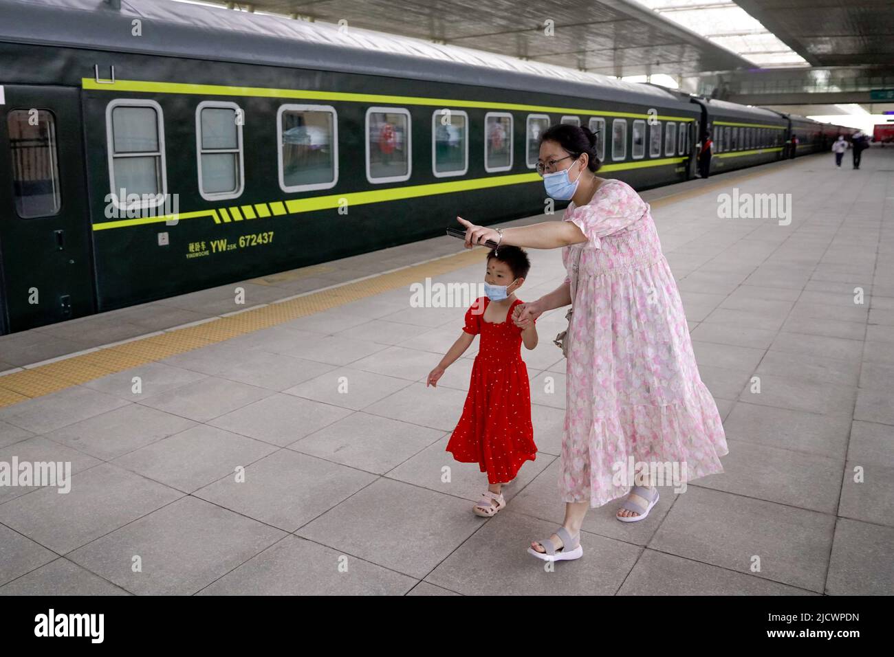 (220616) -- HOTAN, 16. Juni 2022 (Xinhua) -- Passagiere steigen am Hotan Bahnhof in Hotan, nordwestlich der Autonomen Region Xinjiang, in den ersten Zug der Hotan-Ruoqiang-Eisenbahn, ein, der am 16. Juni 2022 an Bord geht. Am Donnerstag wurde der letzte Abschnitt einer 2.712 km langen Eisenbahnstrecke rund um Chinas größte Wüste, die Taklimakan, in der nordwestlichsten Autonomen Region Xinjiang Uygur in Betrieb genommen. Die Eröffnung der Bahnstrecke Hotan-Ruoqiang wird es den Zügen ermöglichen, zum ersten Mal weltweit einen vollen Kreis um eine Wüste zu umrunden, so die China State Railway Group Co., Stockfoto