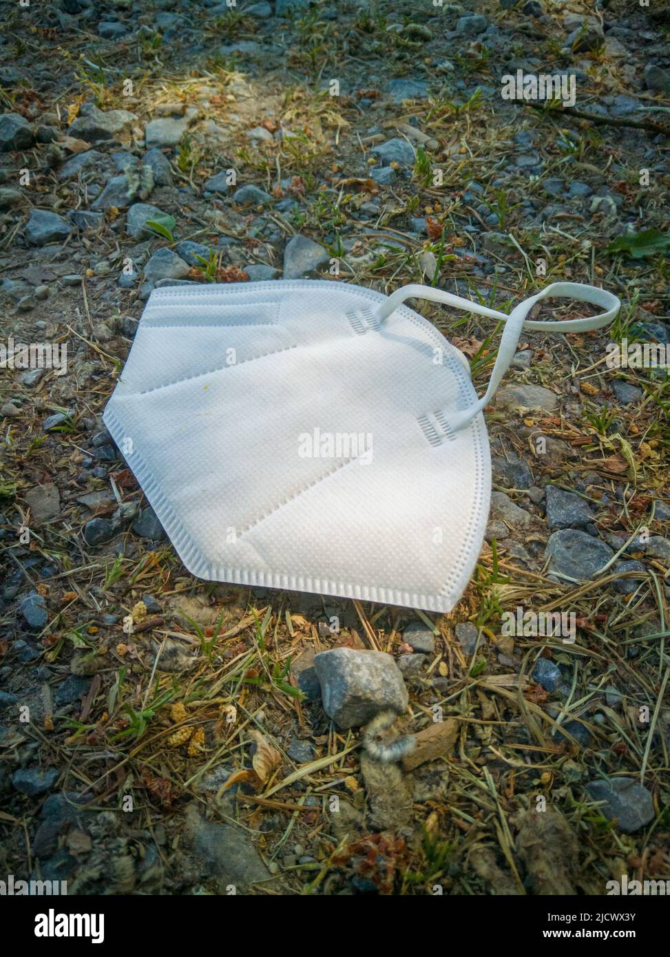 Ausrangierte FFP2-Maske liegt auf der Landstraße. Ein Symbol für Müll und Verschmutzung. Stockfoto