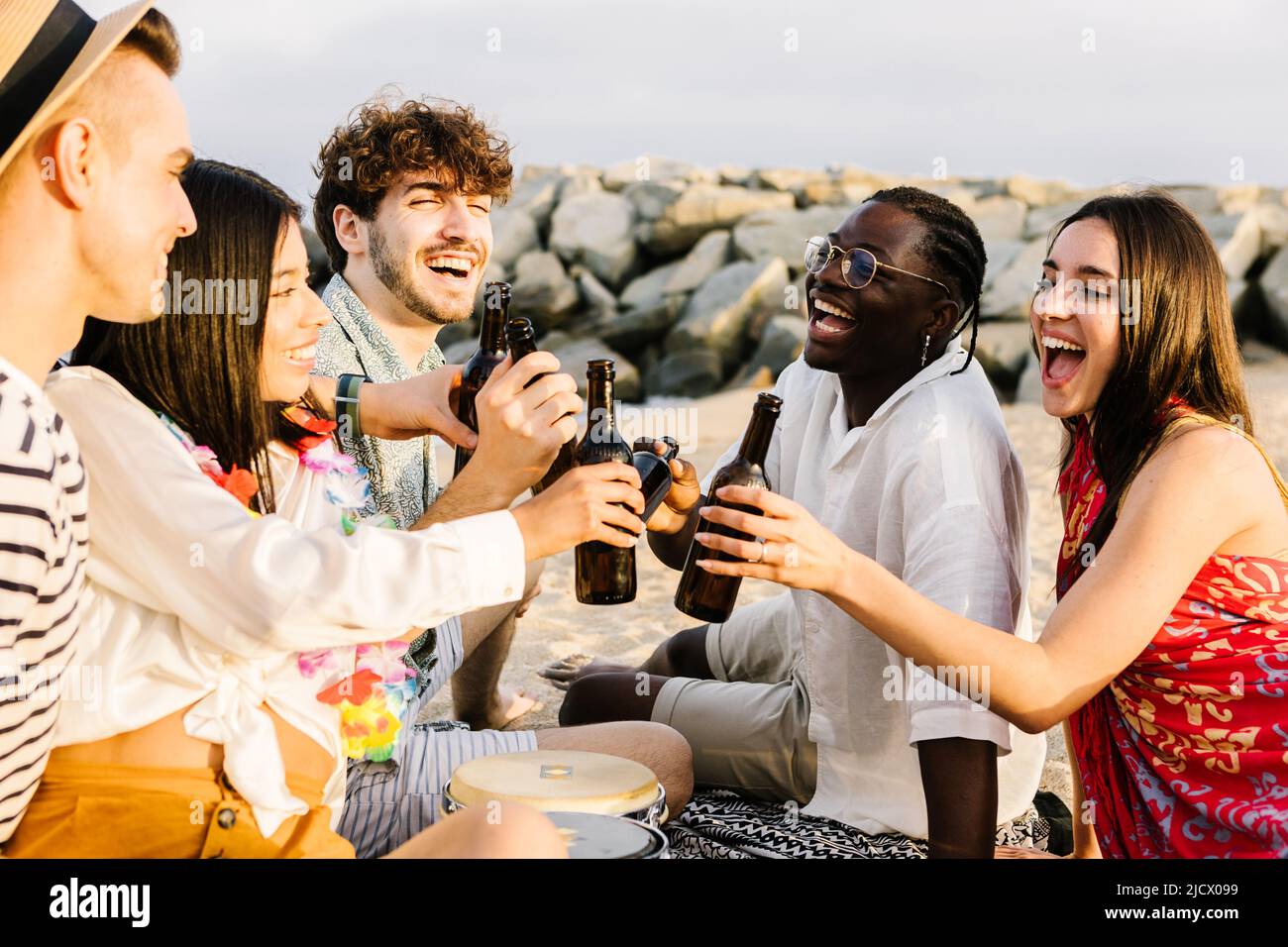 Glückliche Freunde genießen das Wochenende am Strand und jubeln mit Bieren Stockfoto