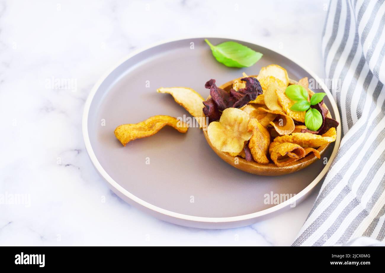 Schüssel mit gesunden Gemüsechips aus Rüben, Süßkartoffeln, Äpfeln, Orangen und Karotten Stockfoto