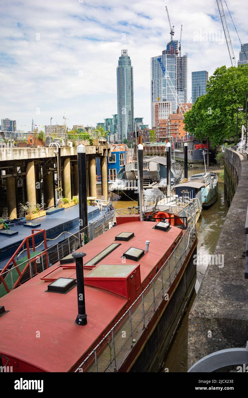 Wohnboote vertäuten in Nine Elms, Vauxhall, London mit dem Tower in der Ferne. Stockfoto