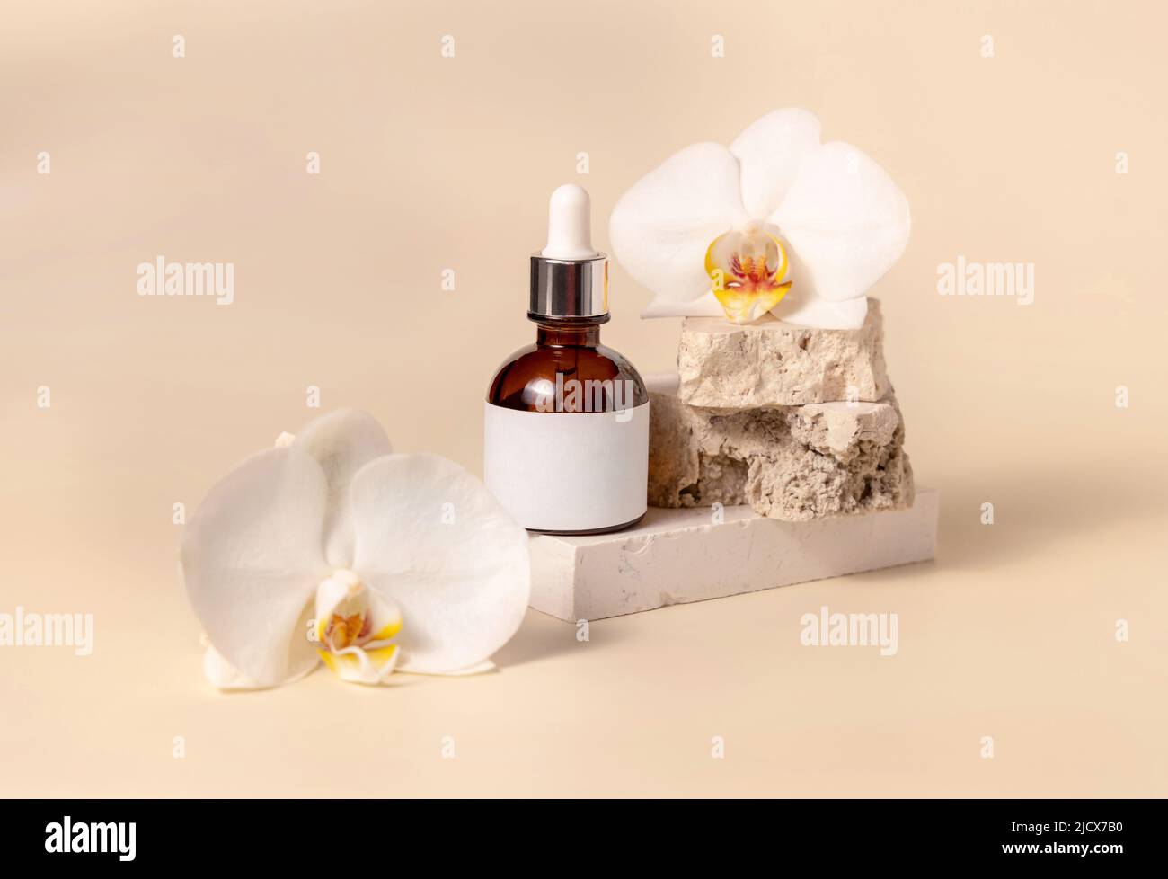 Braune Glasflasche auf Stein in der Nähe von weißen Orchideenblüten auf hellgelb, Nahaufnahme, Mockup. Hautpflege handgemachtes Beauty-Produkt, Serum oder Lotion. Z. B. Stockfoto