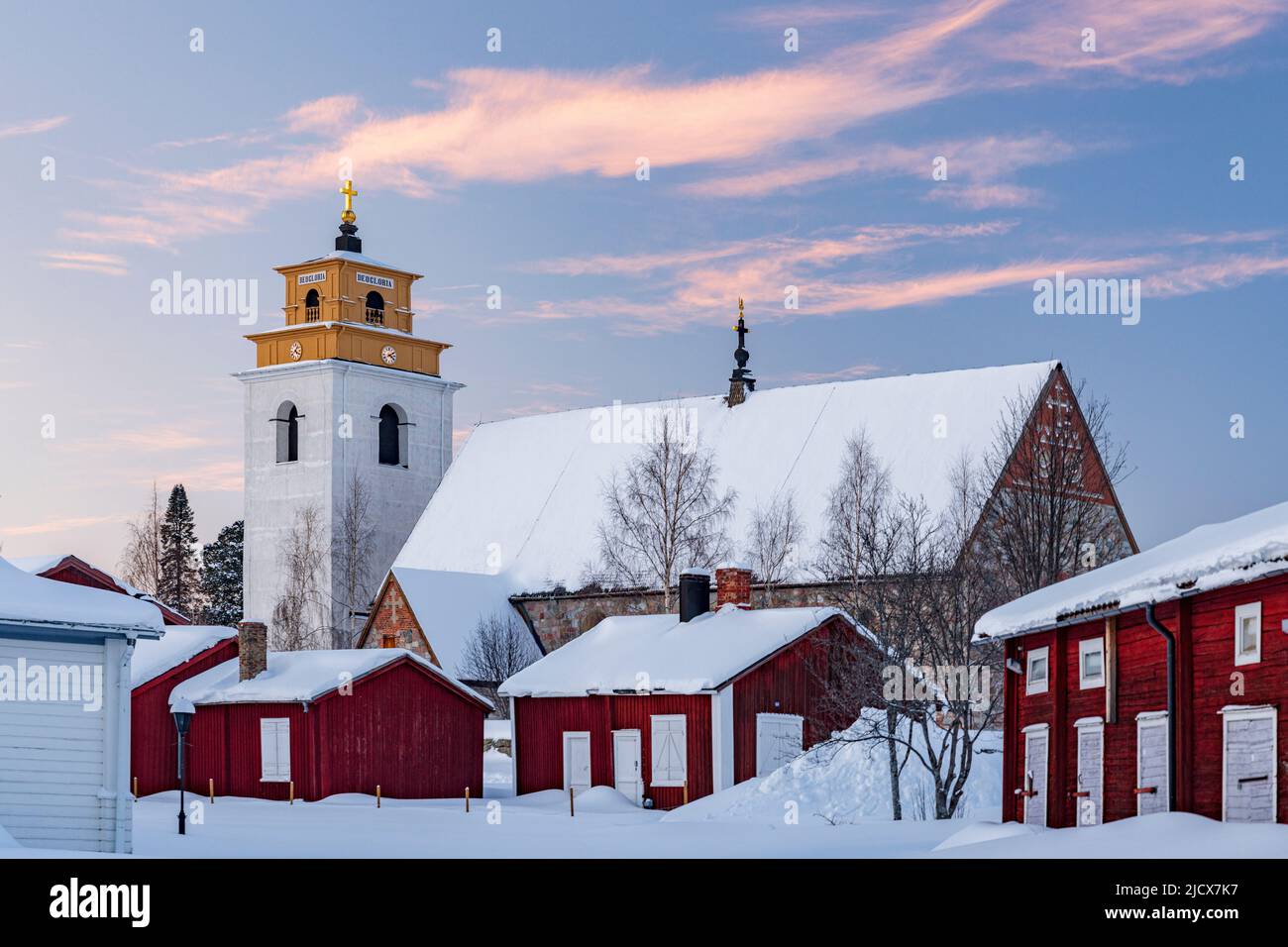 Alte Kirche und malerische Gebäude mit Schnee bei Sonnenuntergang in Gammelstad Altstadt, UNESCO-Weltkulturerbe, Lulea, Schweden, Skandinavien bedeckt Stockfoto