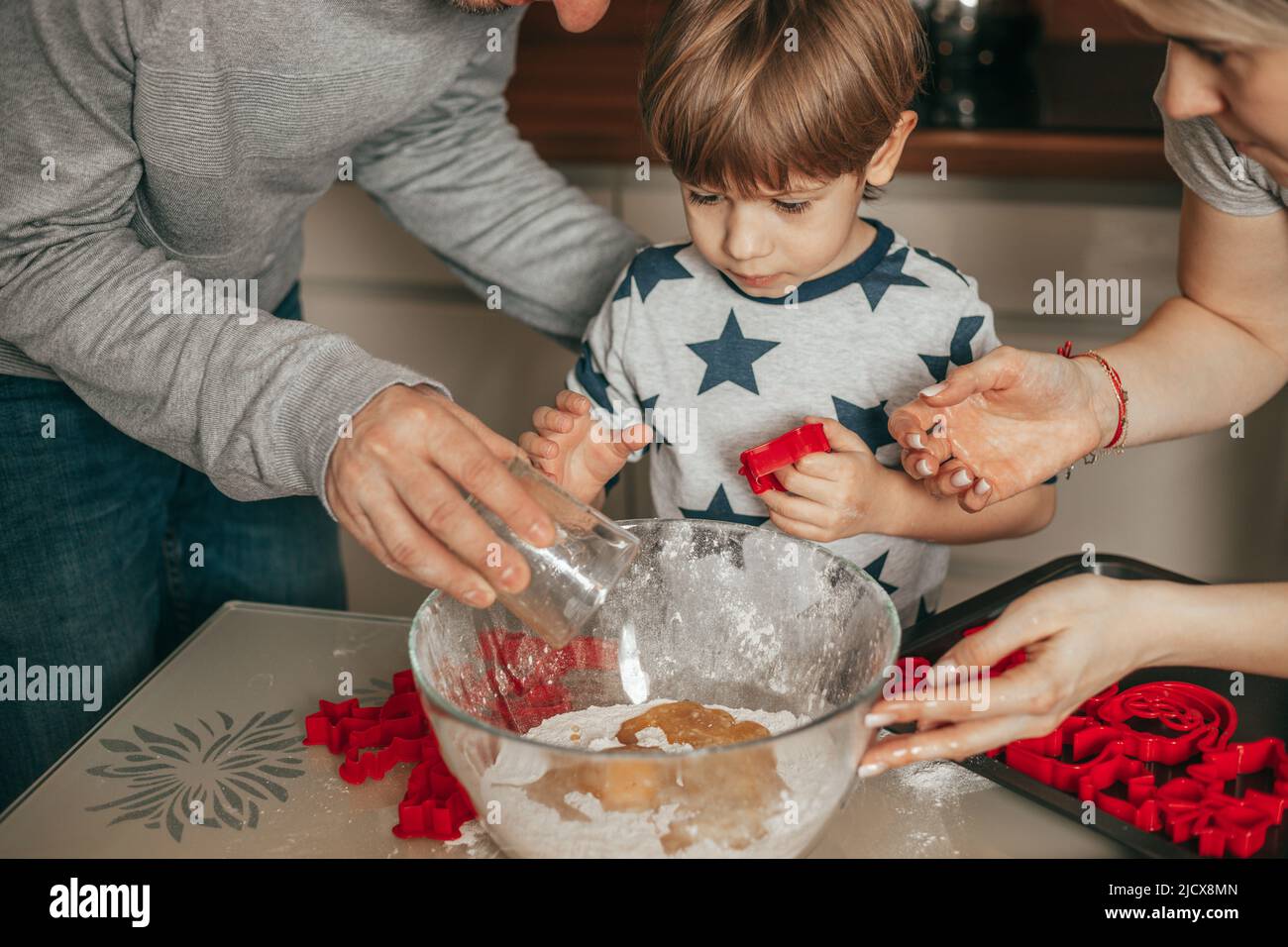 Der kleine Junge, 45 Jahre alt, ist begeistert vom Kneten von Teig. Papa und Mama helfen ihm in der Küche. Frohe Zeit mit der Familie zusammen. Hobby. Teamarbeit. Abgeschlossen Stockfoto