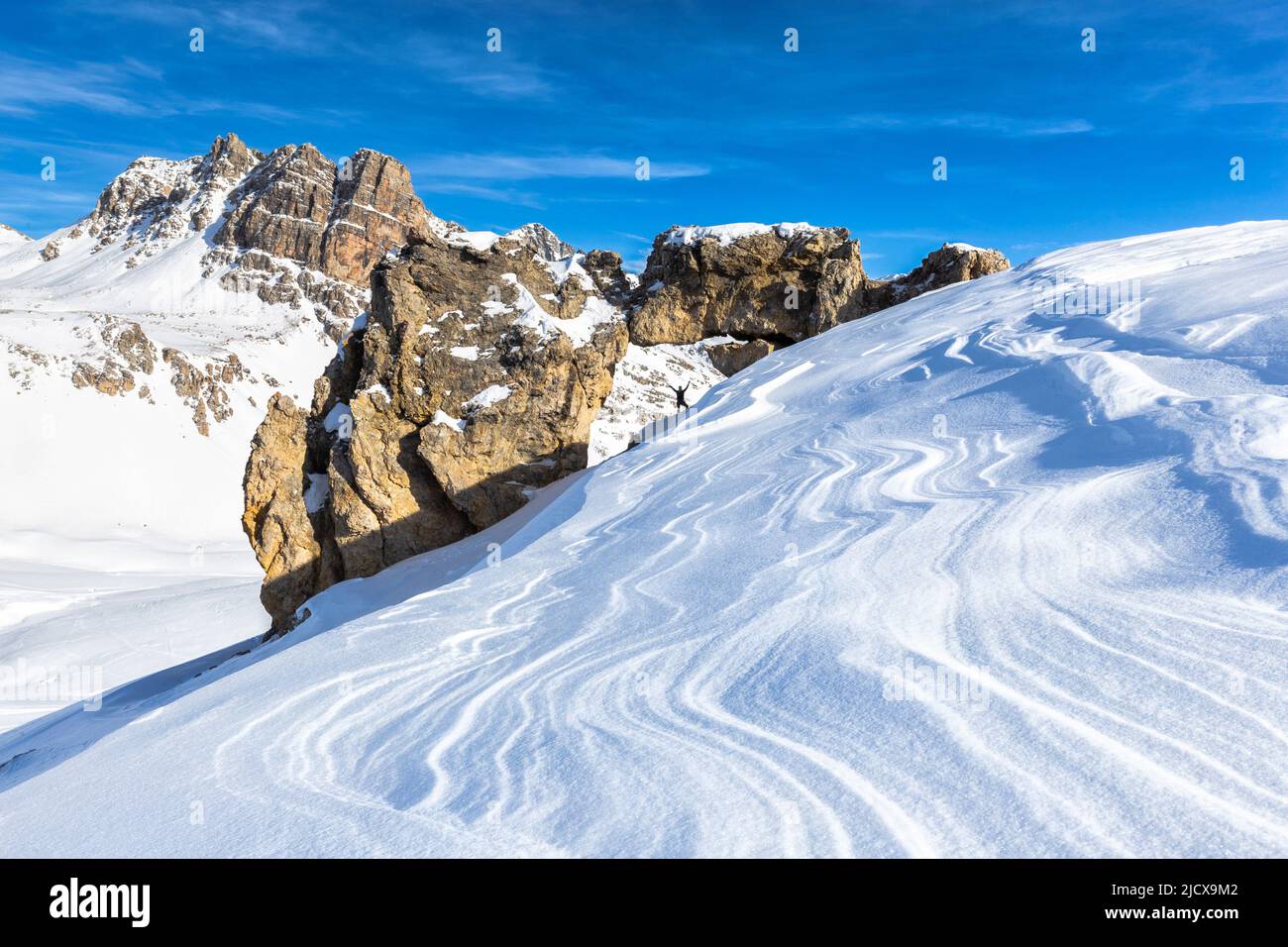 Eine Person und natürlicher Felsbogen mit vom Wind geformtem Schnee im Vordergrund, Julier Pass, Graubünden, Schweiz, Europa Stockfoto
