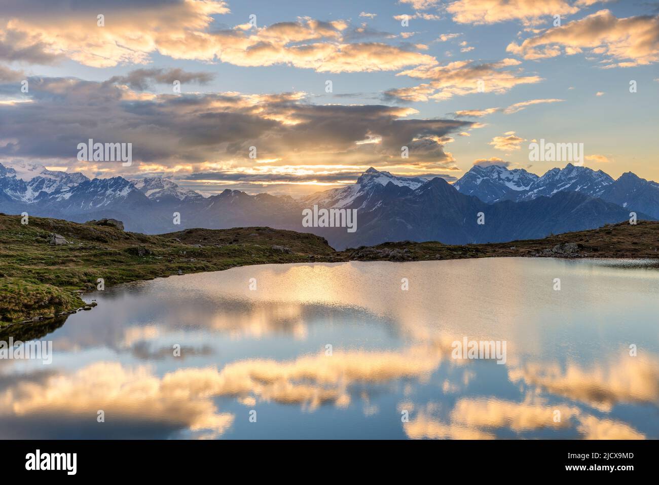 Sonne und Wolken spiegeln sich im Arcoglio-See bei Sonnenaufgang, Valmalenco, Valtellina, Lombardei, Italien, Europa Stockfoto