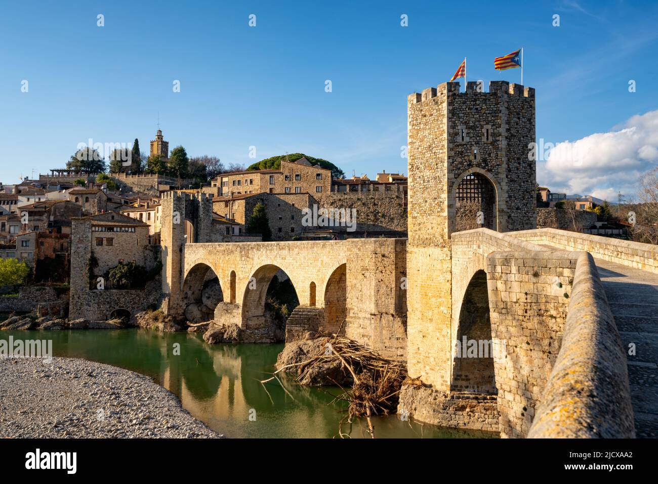 Besalu historische mittelalterliche Stadt mit katalanischen Flaggen auf dem steinernen Brückenturm, der den Fluss El Fluvia, Besalu, Katalonien, Spanien, Europa überquert Stockfoto