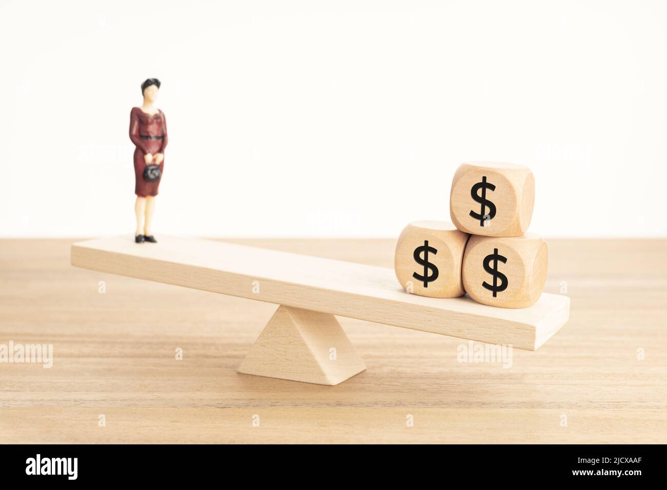 Leben und Arbeit oder Geld Balance Konzept. Geschäftsfrau Figur und Dollar-Symbol auf Holzblöcken auf hölzerner Wippe Stockfoto