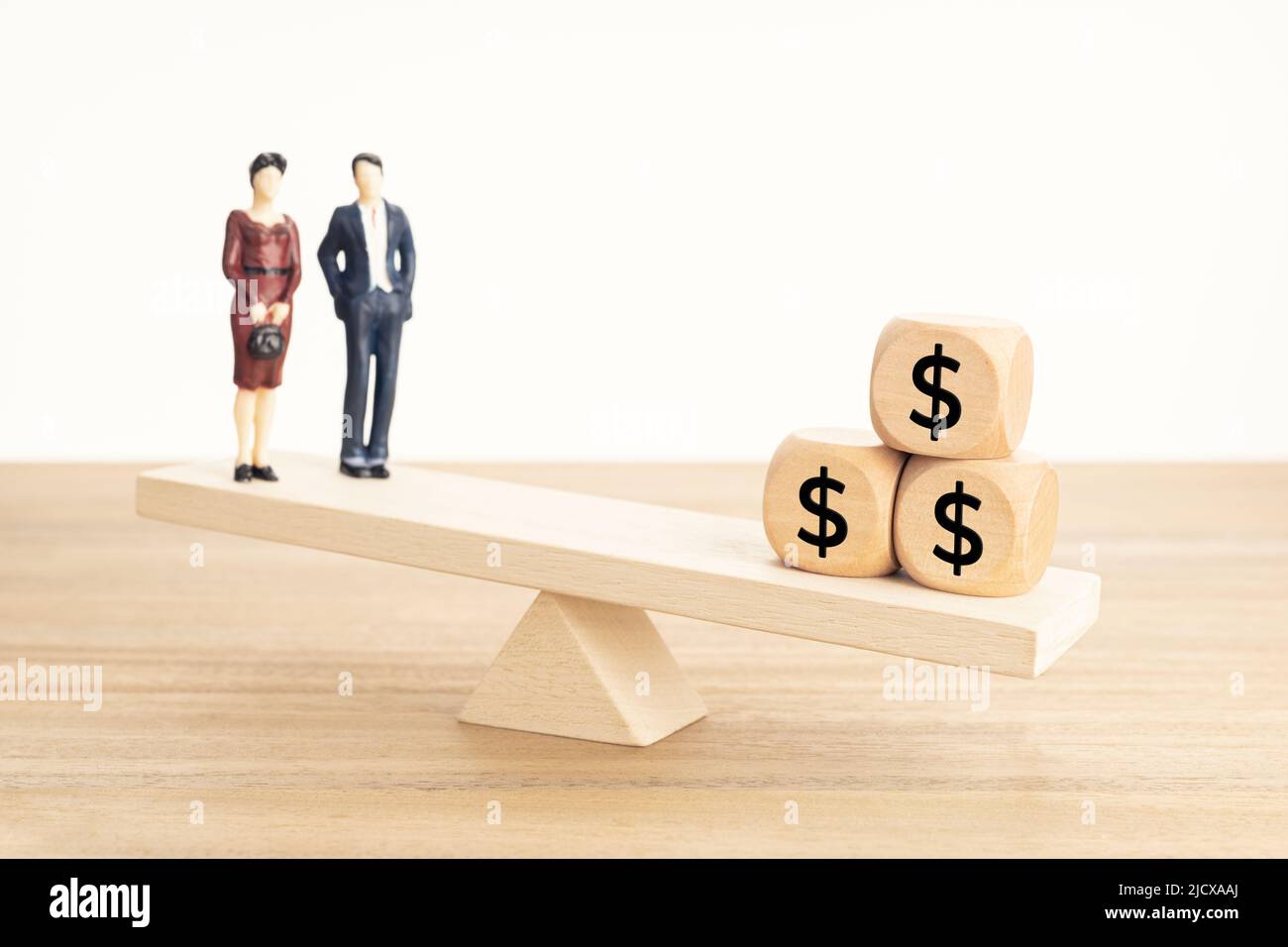 Leben und Arbeit oder Geld Balance Konzept. Paar Figur und Dollar-Symbol auf Holzblöcken auf hölzerner Wippe Stockfoto