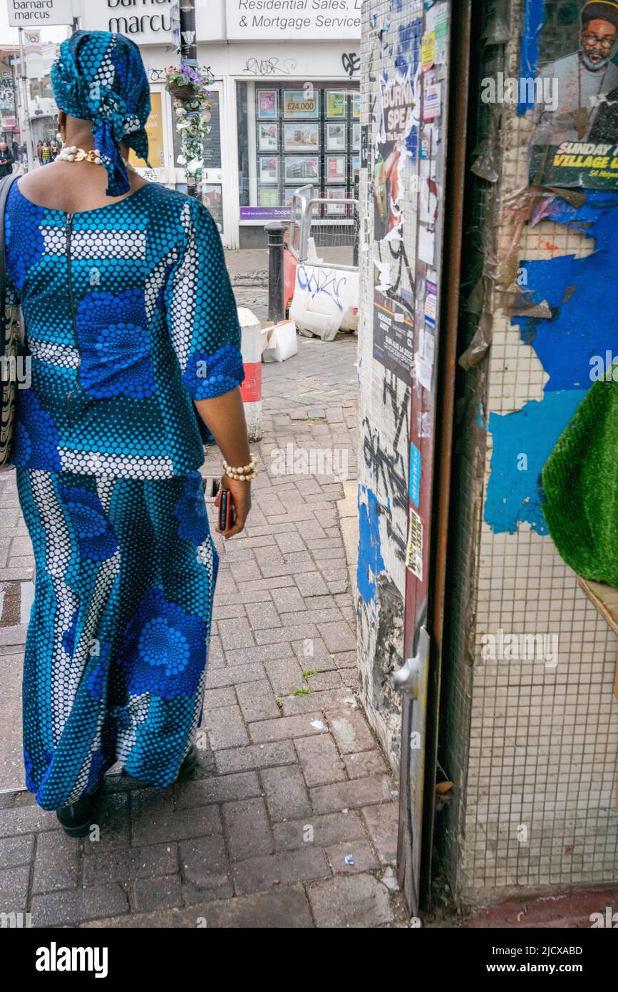 Afro-karibische Frau in einem traditionellen blauen Kleid in Peckham High Street, London, England, Großbritannien Stockfoto