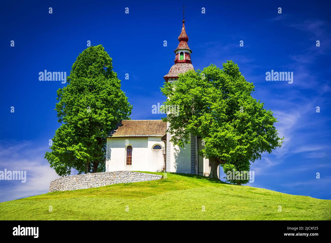 Praprotschno, Skofja Loka - Slowenien. Die auf dem Hügel gelegene Kirche Sveti Tomaz, eine beeindruckende Postkarte der Kamnik-Savinja-Alpen. Stockfoto