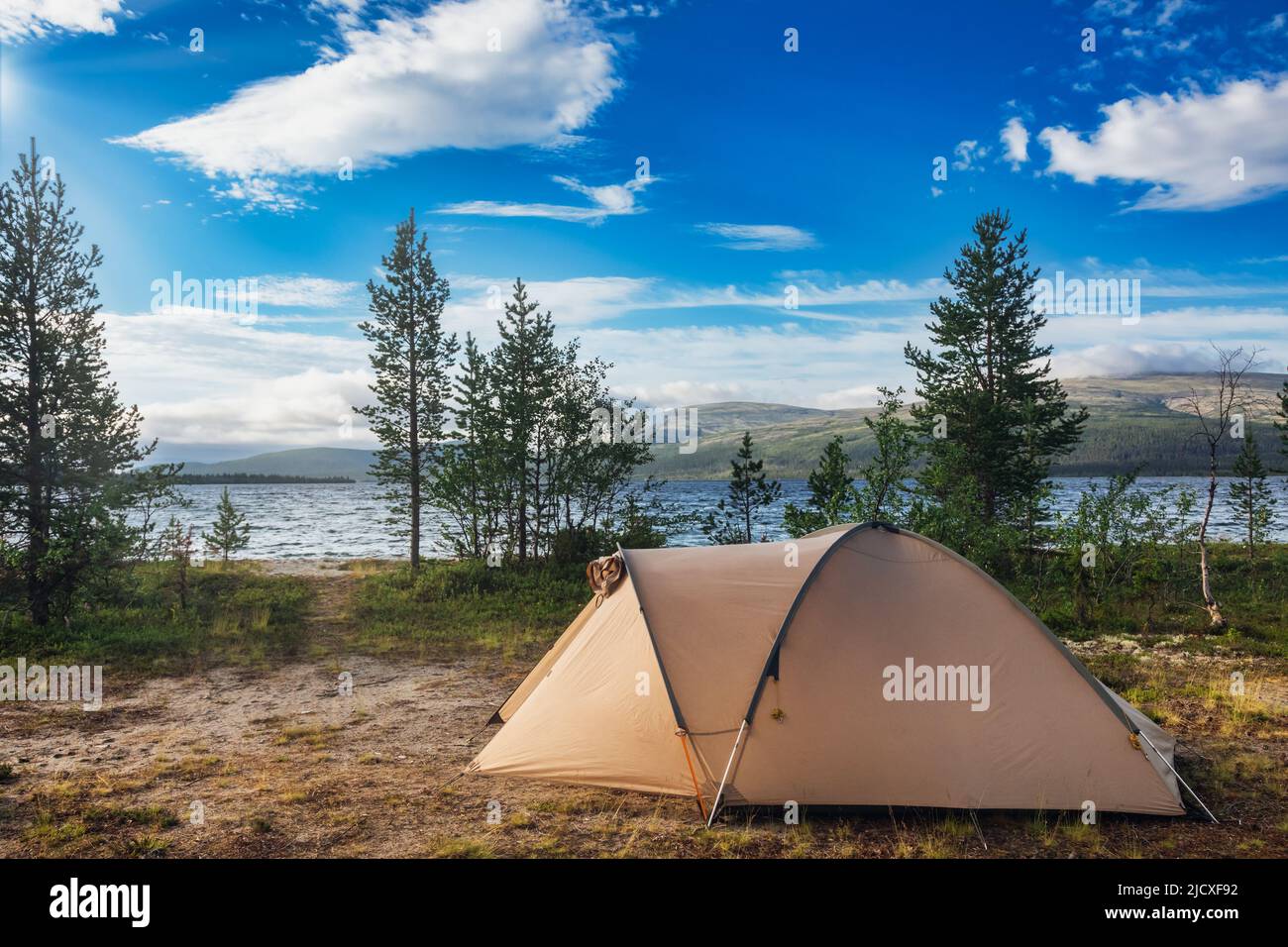 Camping-Zelt auf malerischem Campingplatz an einem Seeufer im Morgenlicht - wildes Camping digitales Detox-Konzept Stockfoto