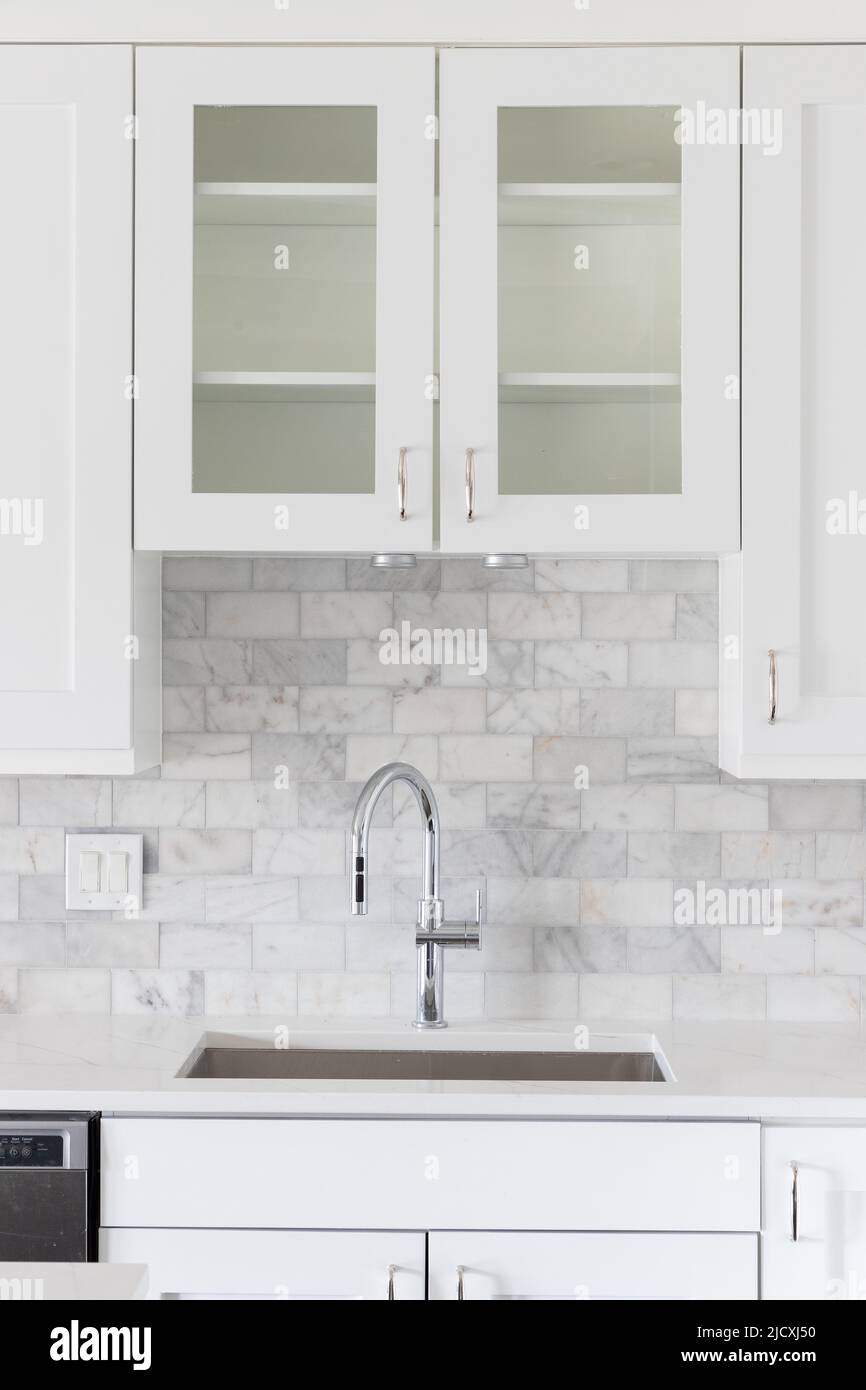 Ein Küchenwaschbecken Detail mit weißen Schränken und einer marmornen U-Bahn-Fliese backsplash aufgenommen. Stockfoto