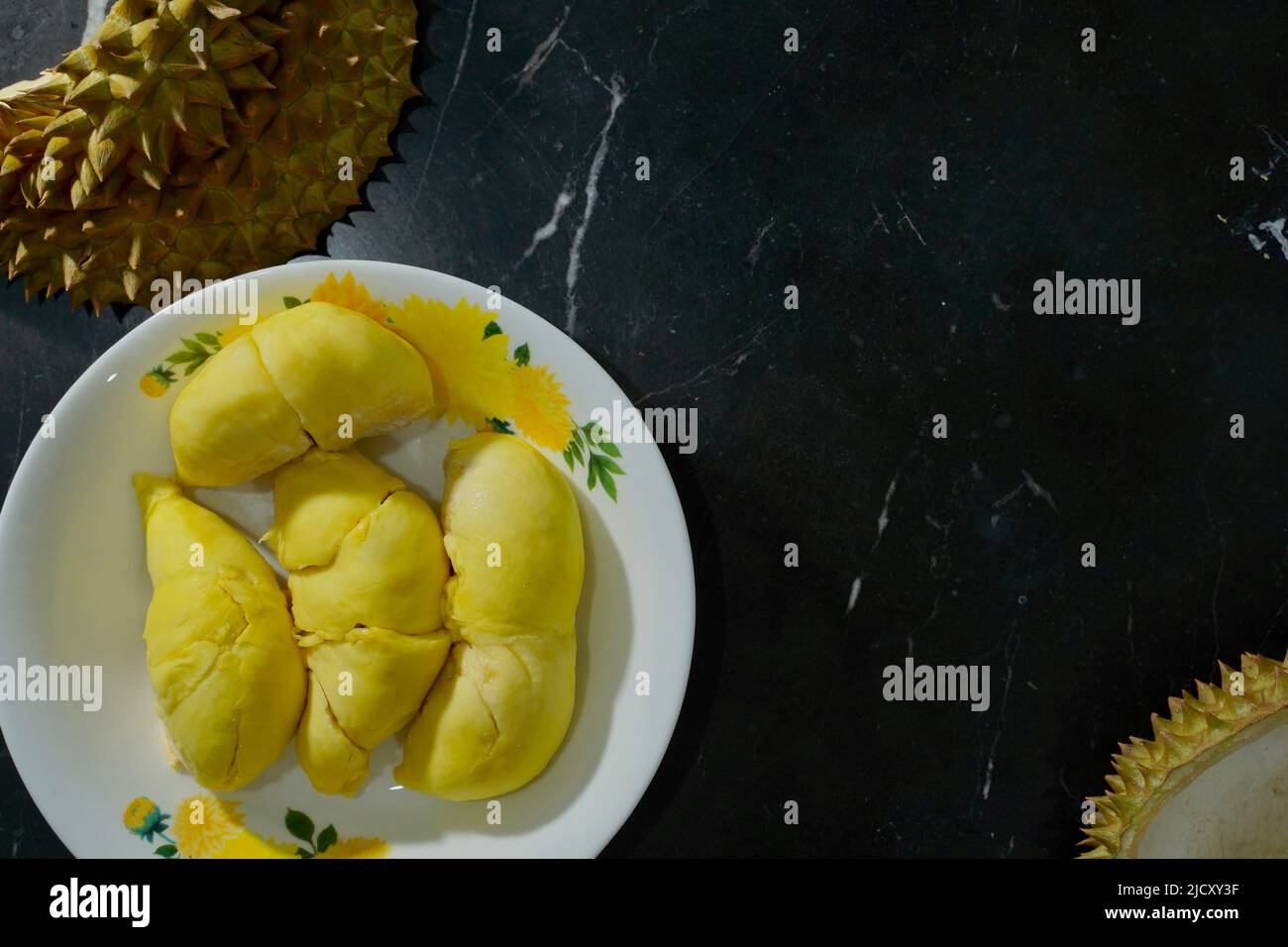 Frischer Durian in der Verpackung auf weißer Schale mit Durian-Schale auf schwarzem Hintergrund des Banners. Durian König der Frucht. Tropische Früchte. Topview von reifen Durian, wo Stockfoto