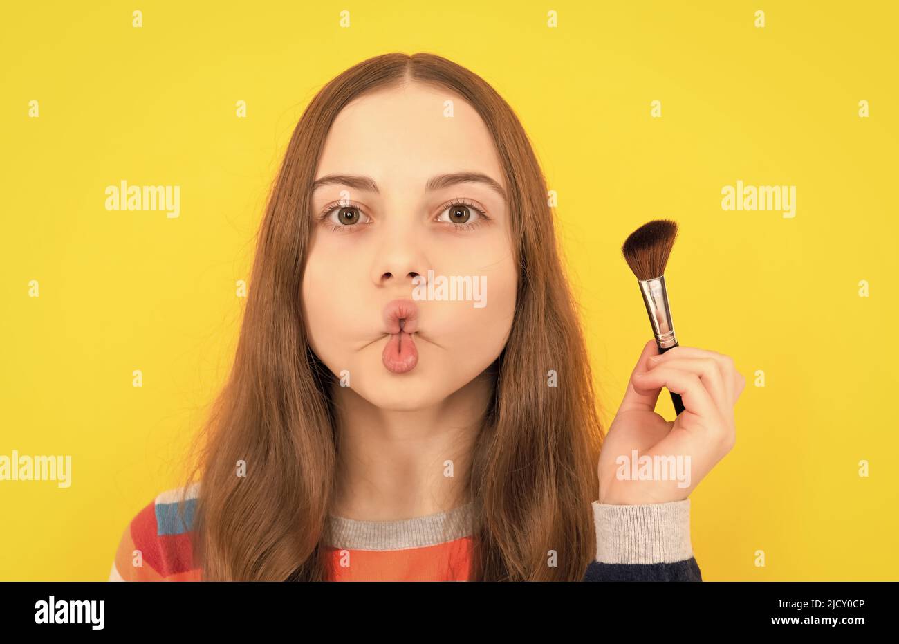 Porträt von Kind, das lustige Fischlippen Gesicht hält Puderbürste für die Anwendung von Kosmetik, Make-up Stockfoto