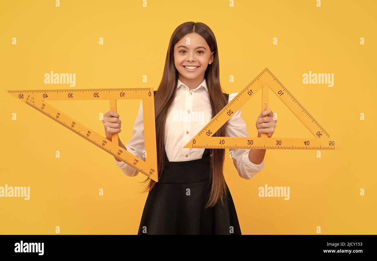 Lächelndes Teenager-Mädchen halten Dreieck. Zurück zur Schule. Algebra und Geometrie. Kind Mathematik lernen. Stockfoto