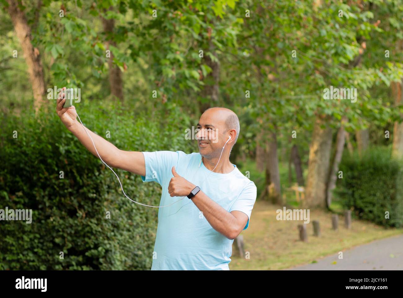Lustiges Selfie eines haarlosen weißen Mannes, der in der Natur einen Videoanruf abgibt und die Kamera anlächelt Stockfoto