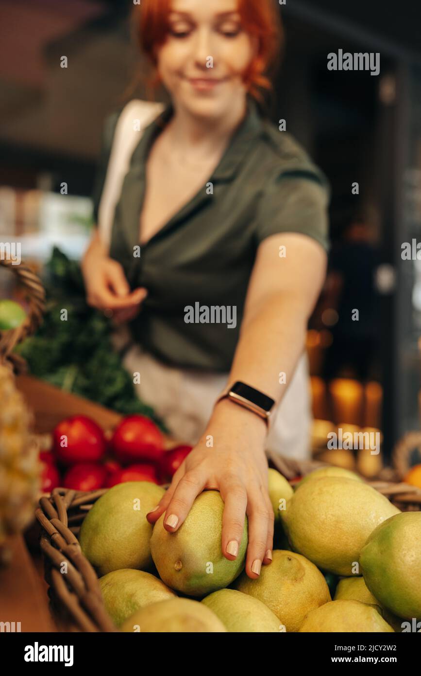 Weibliche Kundin pflücken einige Bio-Früchte in der Frischeabteilung eines Lebensmittelladens. Glückliche junge Frau einkaufen in einem trendigen Supermarkt Stockfoto