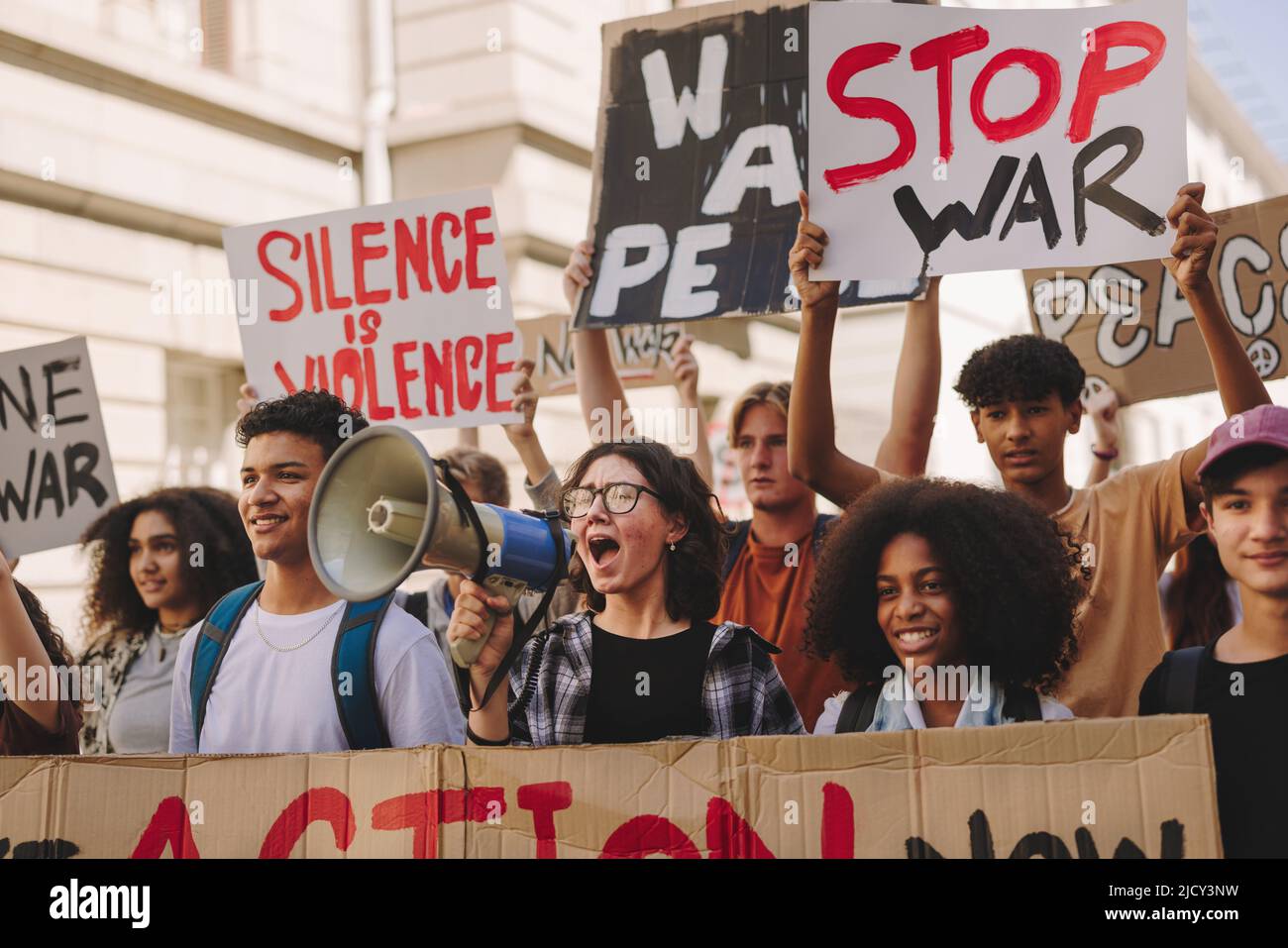 Gruppe multikultureller Jugendaktivisten, die in den Straßen der Stadt gegen Krieg und Gewalt protestieren. Demonstranten der Generation Z rufen Slogans und Rais Stockfoto