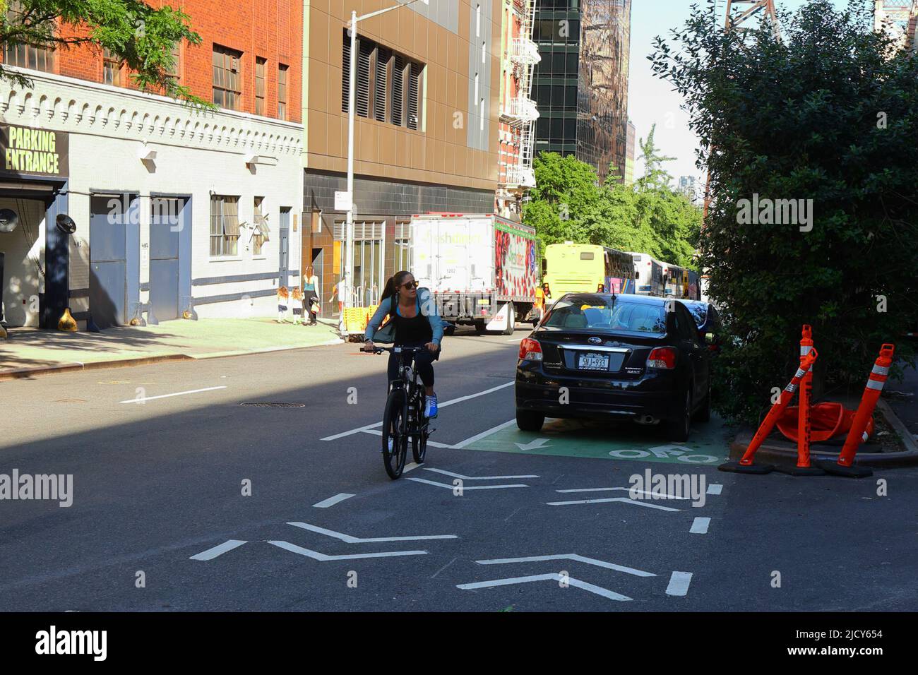 Ein Fahrradfahrer umherfährt mehrere geparkte Autos, die eine Zweiwege-Fahrradspur in New York City blockieren. Stockfoto