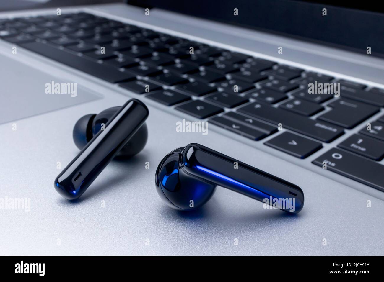 Schwarze kabellose Kopfhörer über dem Laptop auf dem Tischhintergrund Stockfoto