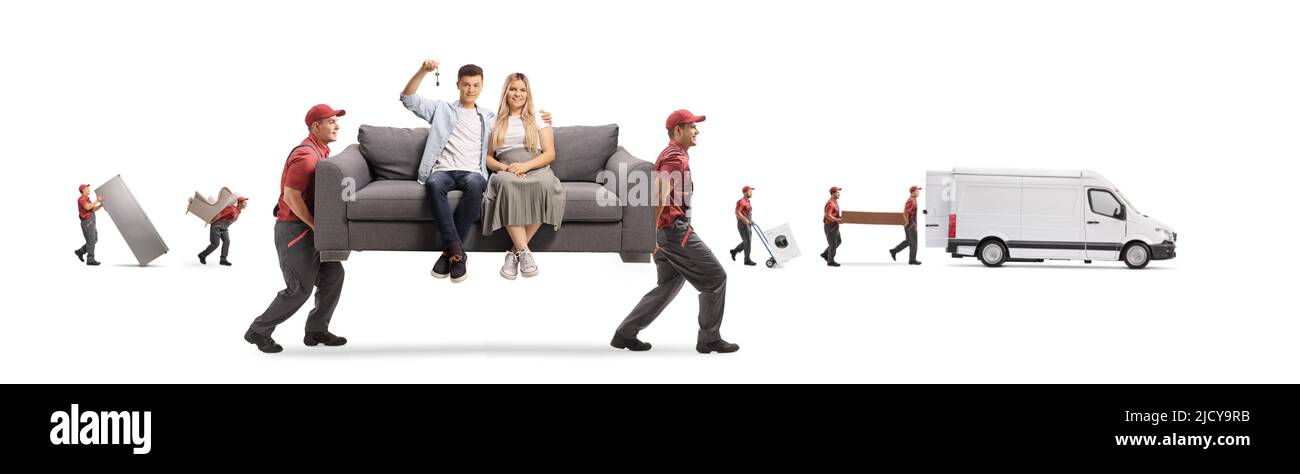 Arbeiter einer Umzugsfirma, die ein junges Paar auf einem grauen Sofa trägt und einen isolierten Hausschlüssel auf weißem Hintergrund hält Stockfoto