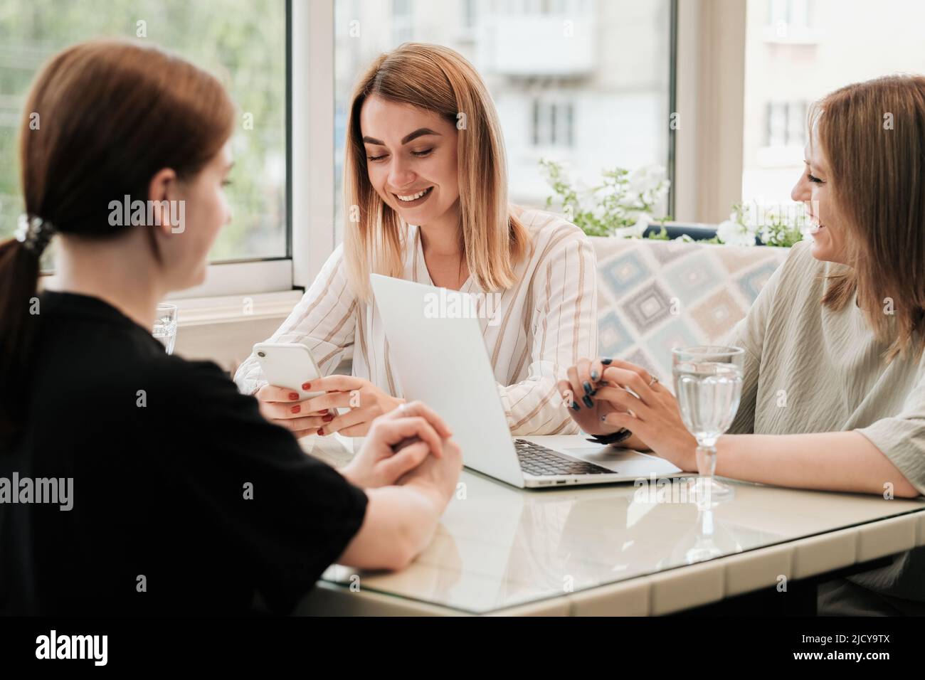 Drei junge und fröhliche Frauen treffen sich zum Mittagessen im Restaurant Stockfoto