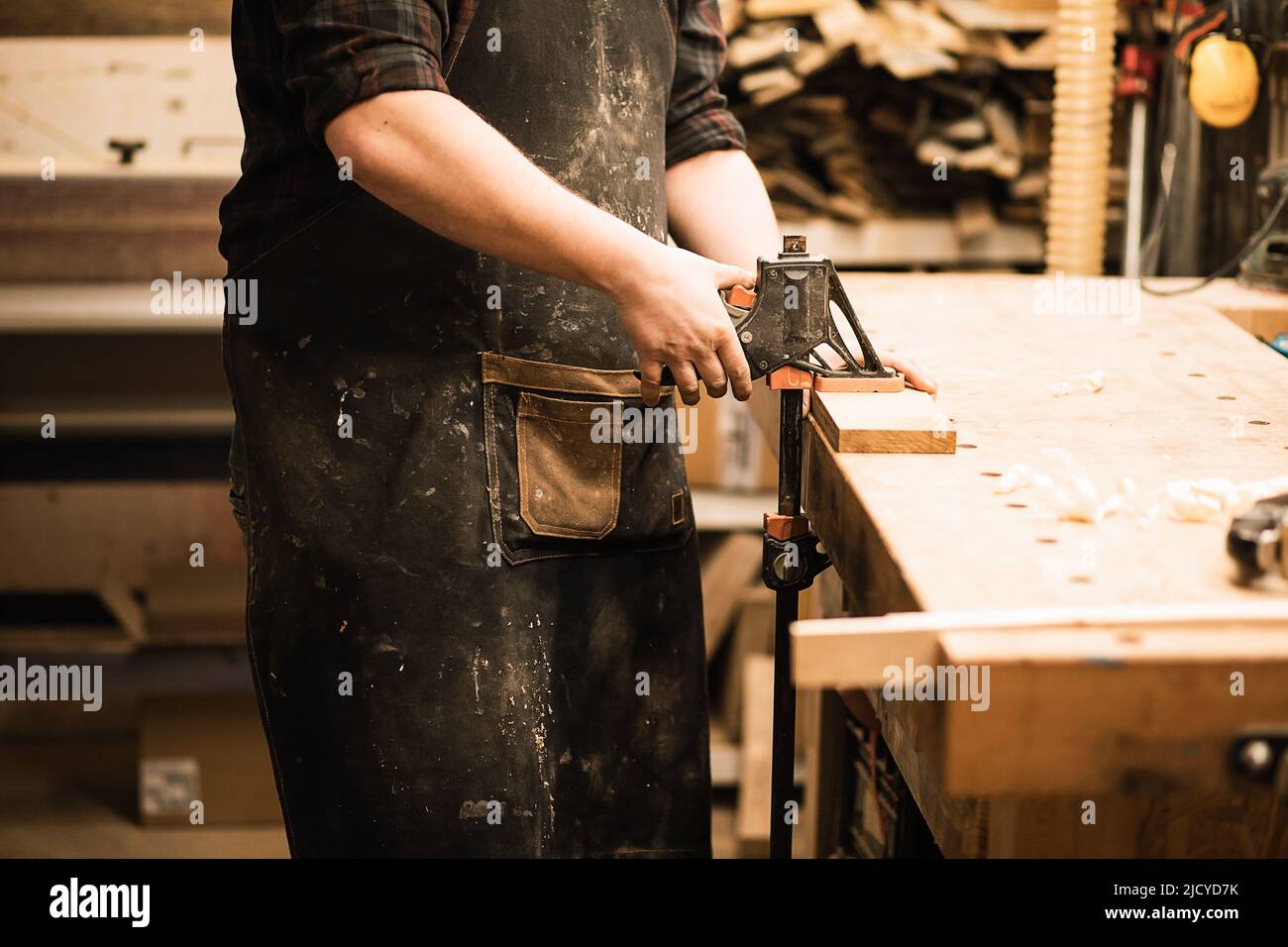Nicht erkennbarer, zugeschnittenes Mann, Zimmermann, der in der Werkstatt eine Planke mit Bandsäge auf einem Arbeitstisch abschneidet Stockfoto