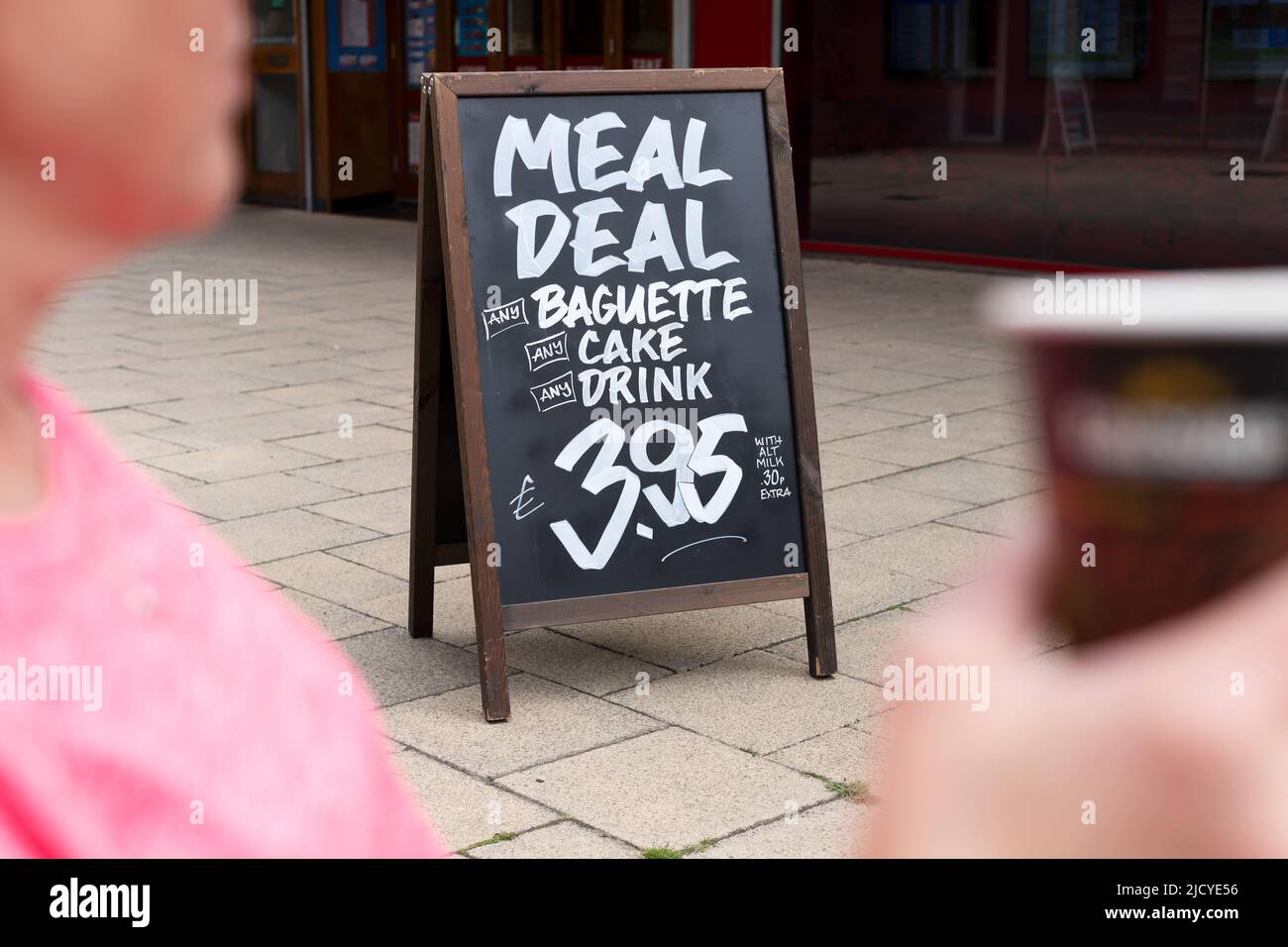 Ein Sandwich-Schild in einem britischen Einkaufsviertel, auf dem ein günstiges Angebot für eine Mahlzeit in einer nahegelegenen Bäckerei steht. Das Angebot umfasst ein Getränk, Kuchen und Baguette Stockfoto