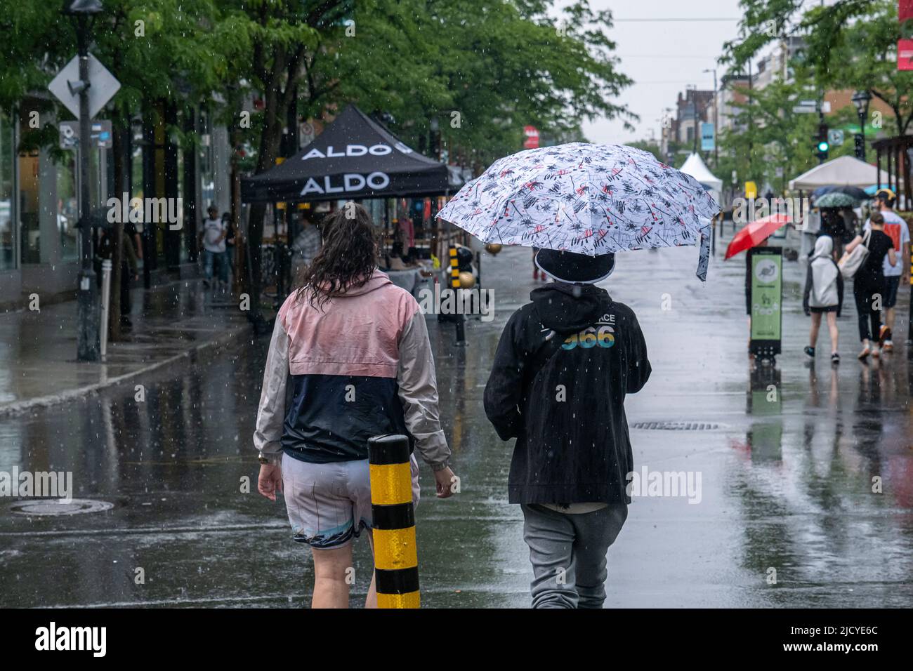 Montreal, CA - 12. Juni 2022: Menschen auf der Mont-Royal Avenue mit Regenschirm bei Regen und Sturm Stockfoto