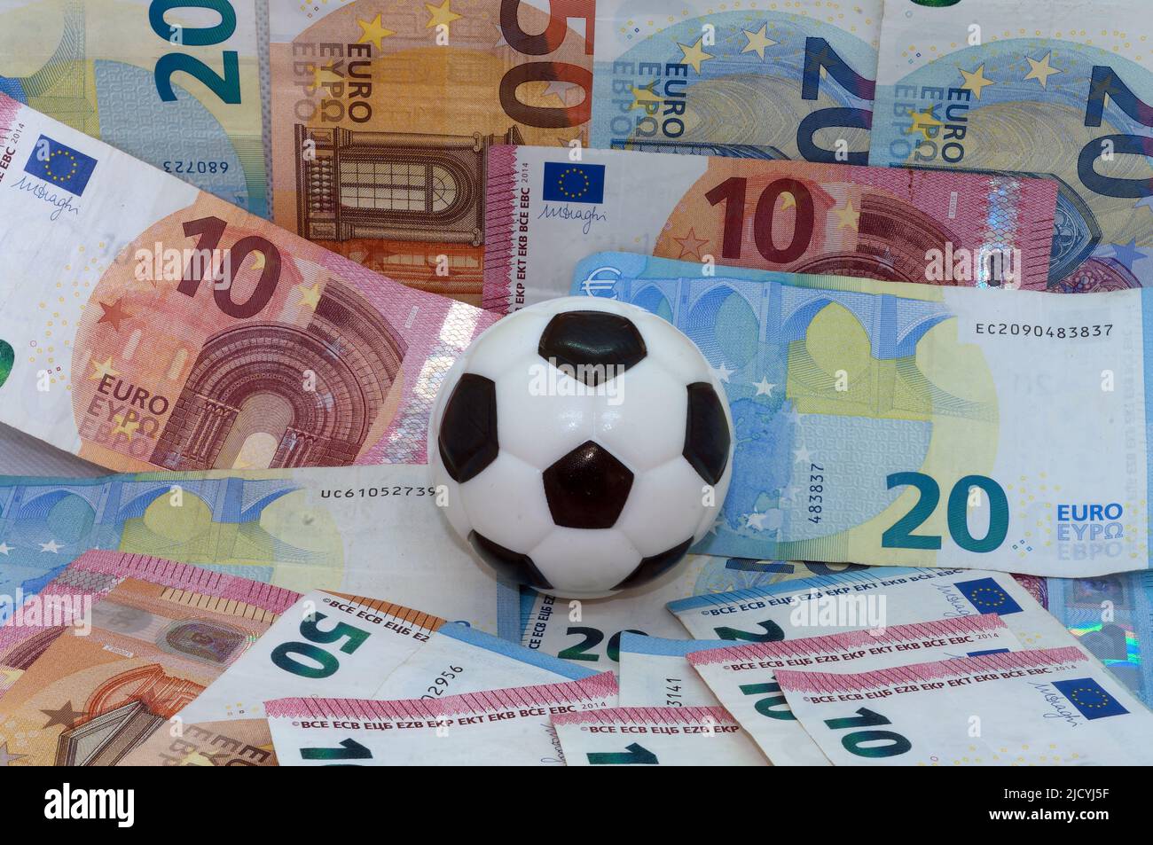 Symbolbild: Sport und Geld, Fußball vor dem Hintergrund von Banknoten Stockfoto