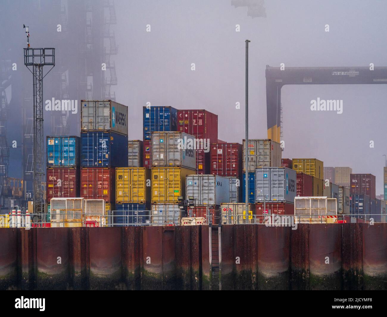 Welthandelsprobleme - durch Nebel isolierte Schiffscontainer an einem Kai in einem britischen Containerhafen. Stockfoto