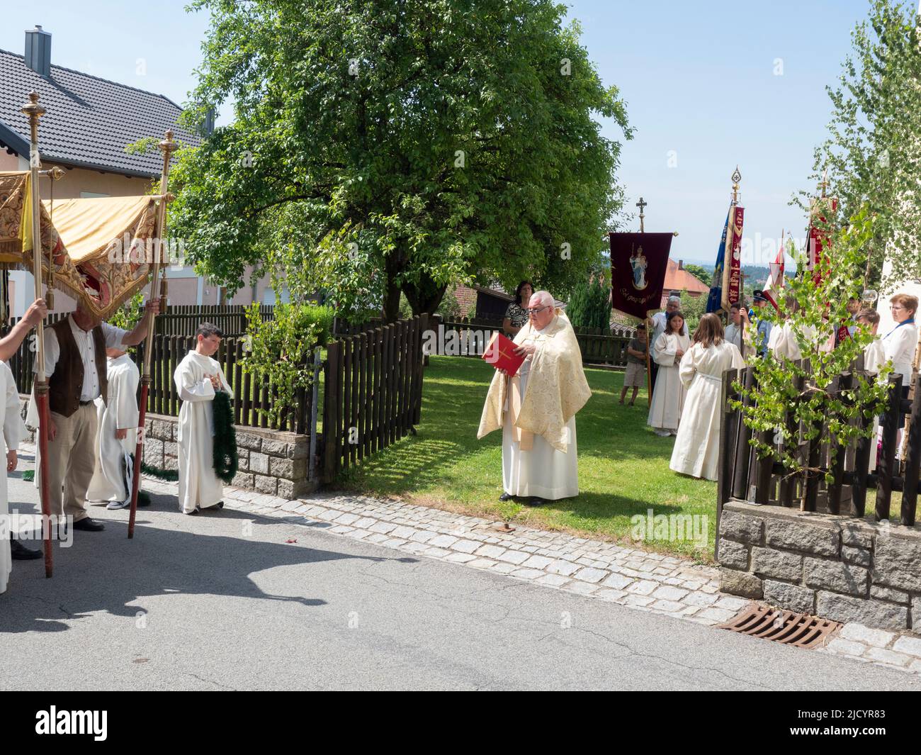 Während der Prozession liest der Priester vor den Gemeindemitgliedern auf der Straße eine Predigt vor. Katholiken des Dorfes Garham machen eine Prozession zu Ehren der Feier des Leibes und Blutes Jesu Christi. Stockfoto