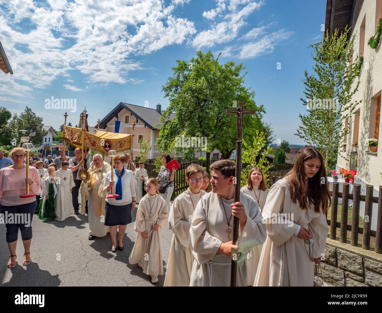 Die Teilnehmer der Prozession tragen Kreuze und einen Baldachin über dem Priester. Katholiken des Dorfes Garham machen eine Prozession zu Ehren der Feier des Leibes und Blutes Jesu Christi. Stockfoto