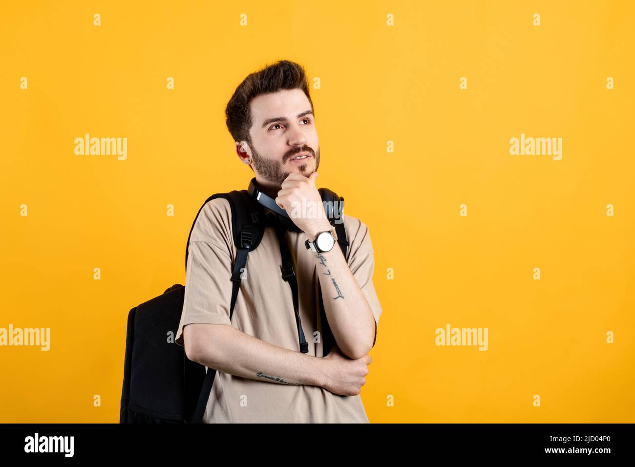 Junger Mann trägt beige T-Shirt posiert isoliert über gelben Hintergrund ernstes Gesicht denken über Frage, sehr verwirrt Idee Stockfoto