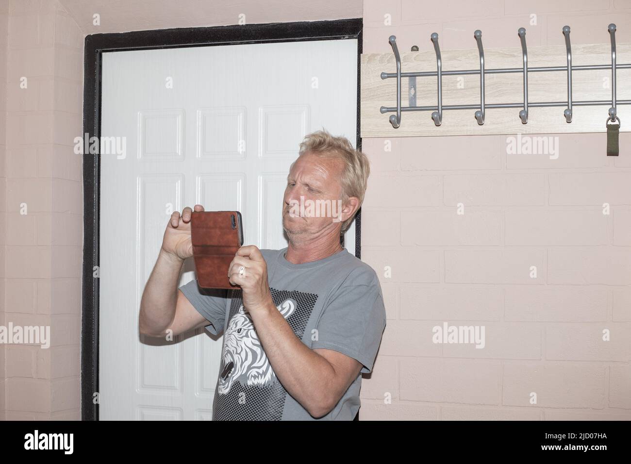 Ein Mann mit einem Telefon im Flur fotografiert das Innere einer kleinen Wohnung. Kauf und Verkauf von Immobilien. Stockfoto