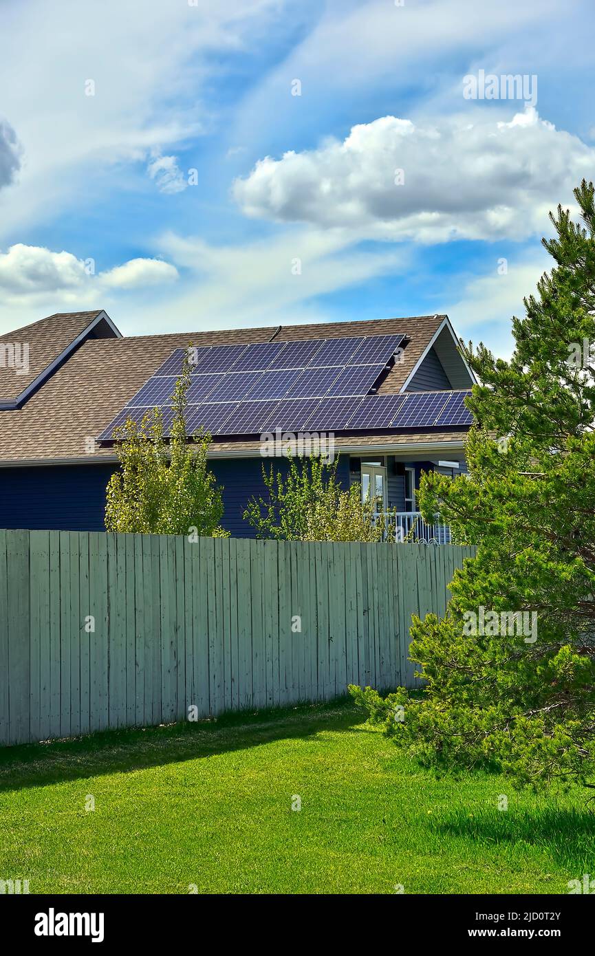 Eine Reihe von Sonnenkollektoren auf einem Hausdach platziert, um das Licht der Sonne für die Energie zu sammeln, um das Haus zu betreiben Stockfoto