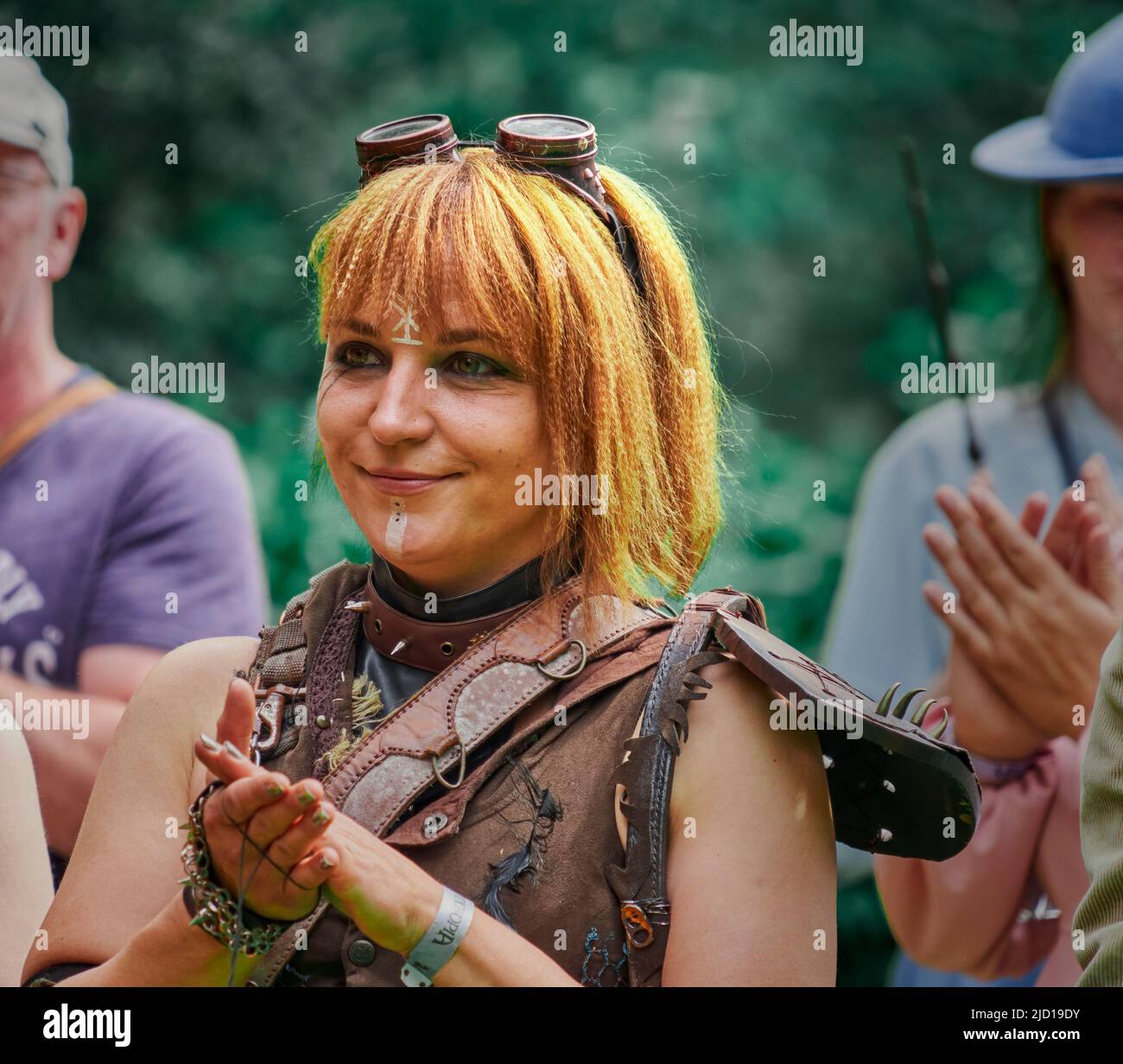 Pattensen, 4. Juni 2022: Lächelnde rothaarige junge Frau im Lederkostüm klatscht beim öffentlichen Fantasy-Festival in die Hände Stockfoto