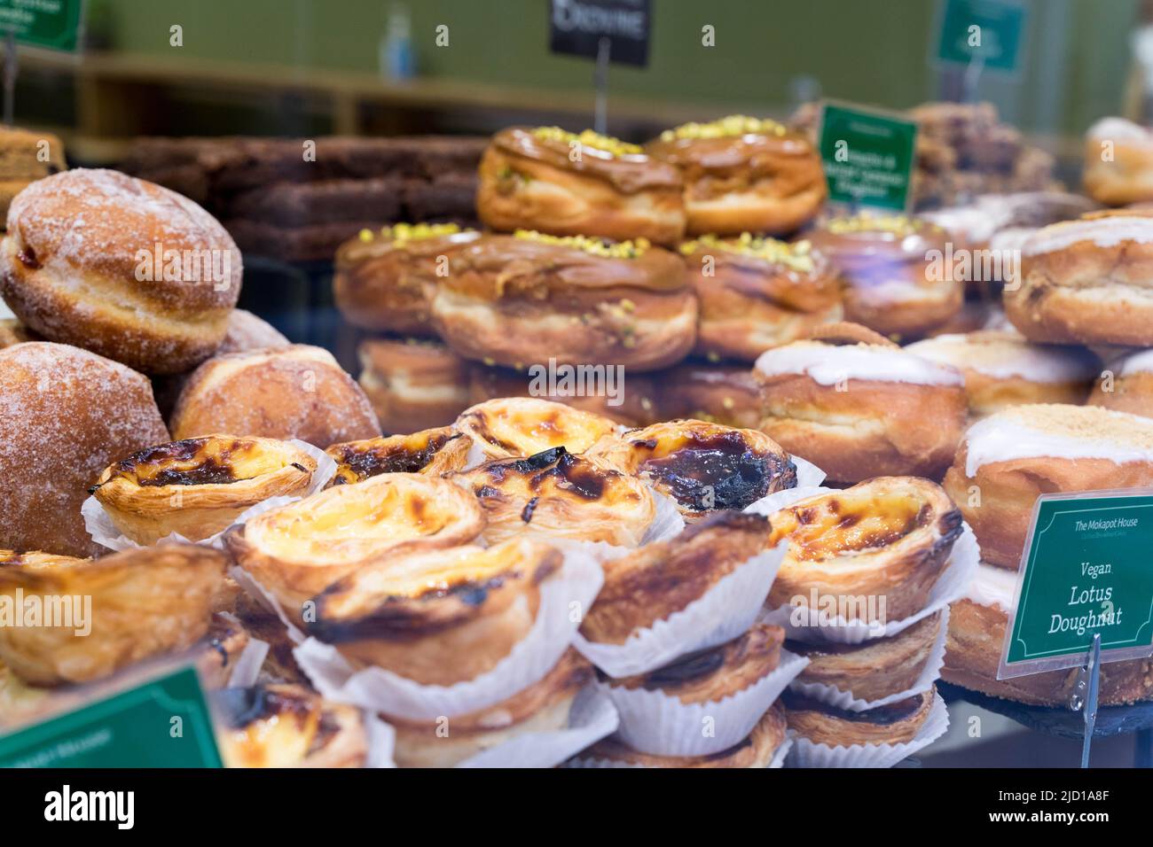 Ein Tablett mit Pastell de nata unter anderem Kuchen und Donuts zum Verkauf London England UK Stockfoto