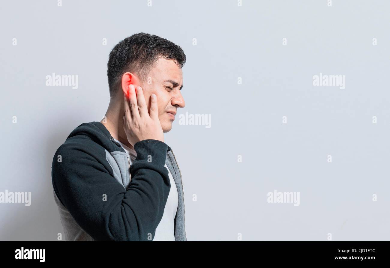 Eine Person mit Otitis und Tinnitus, Person mit Ohrschmerzen, auf isoliertem Hintergrund, leidenden Mann massiert sein Ohr isoliert Stockfoto
