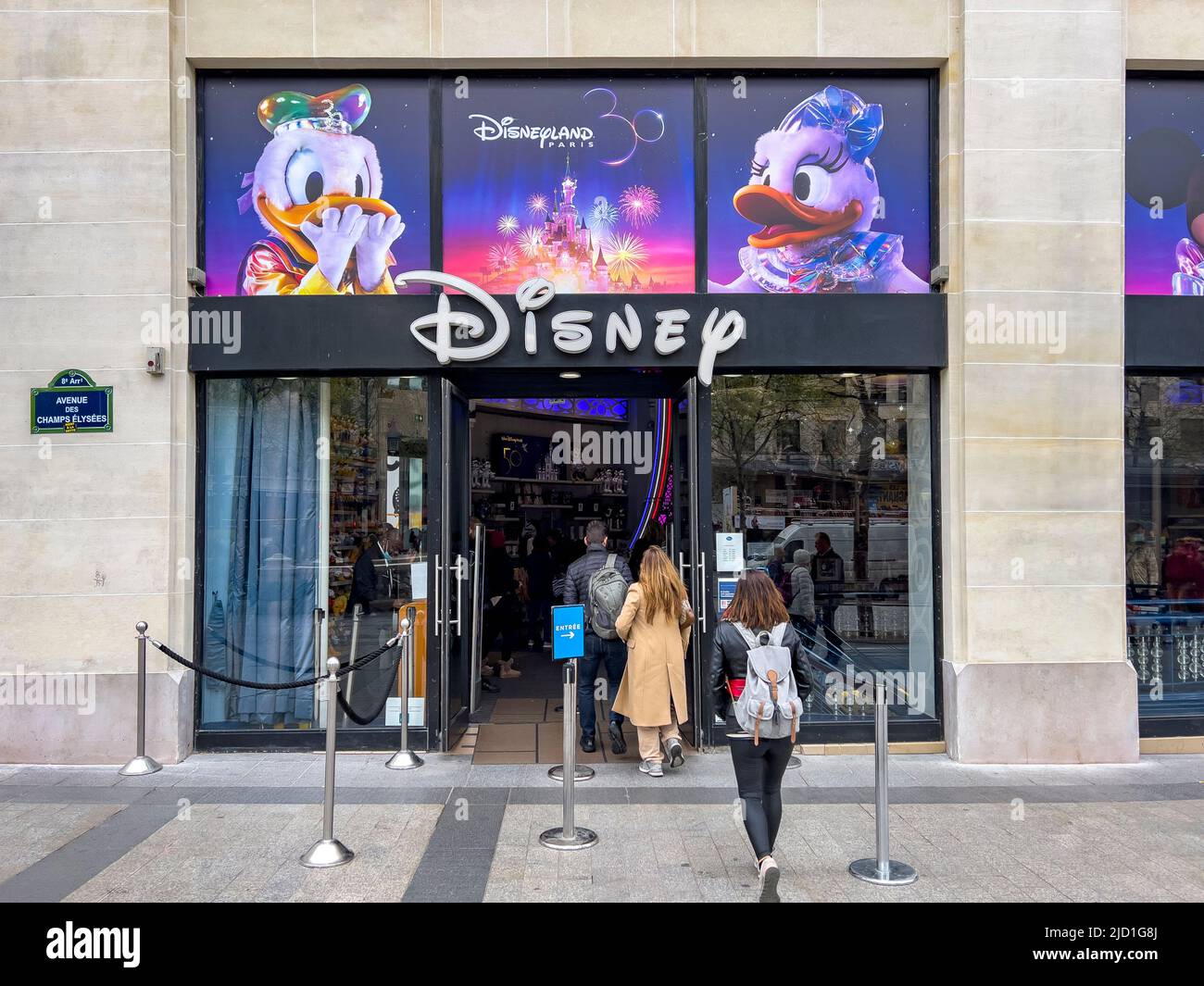 Paris, Frankreich. 06.17.2022. Disney Store-Eingangsschild an der berühmten Champs Elysees Avenue. Die Rückansicht der Menschen steht vor der Tür. 30 Jahre Stockfoto