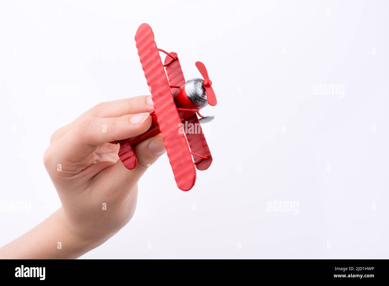 Hand hält eine rote Spielflugzeug auf weißem Hintergrund Stockfoto