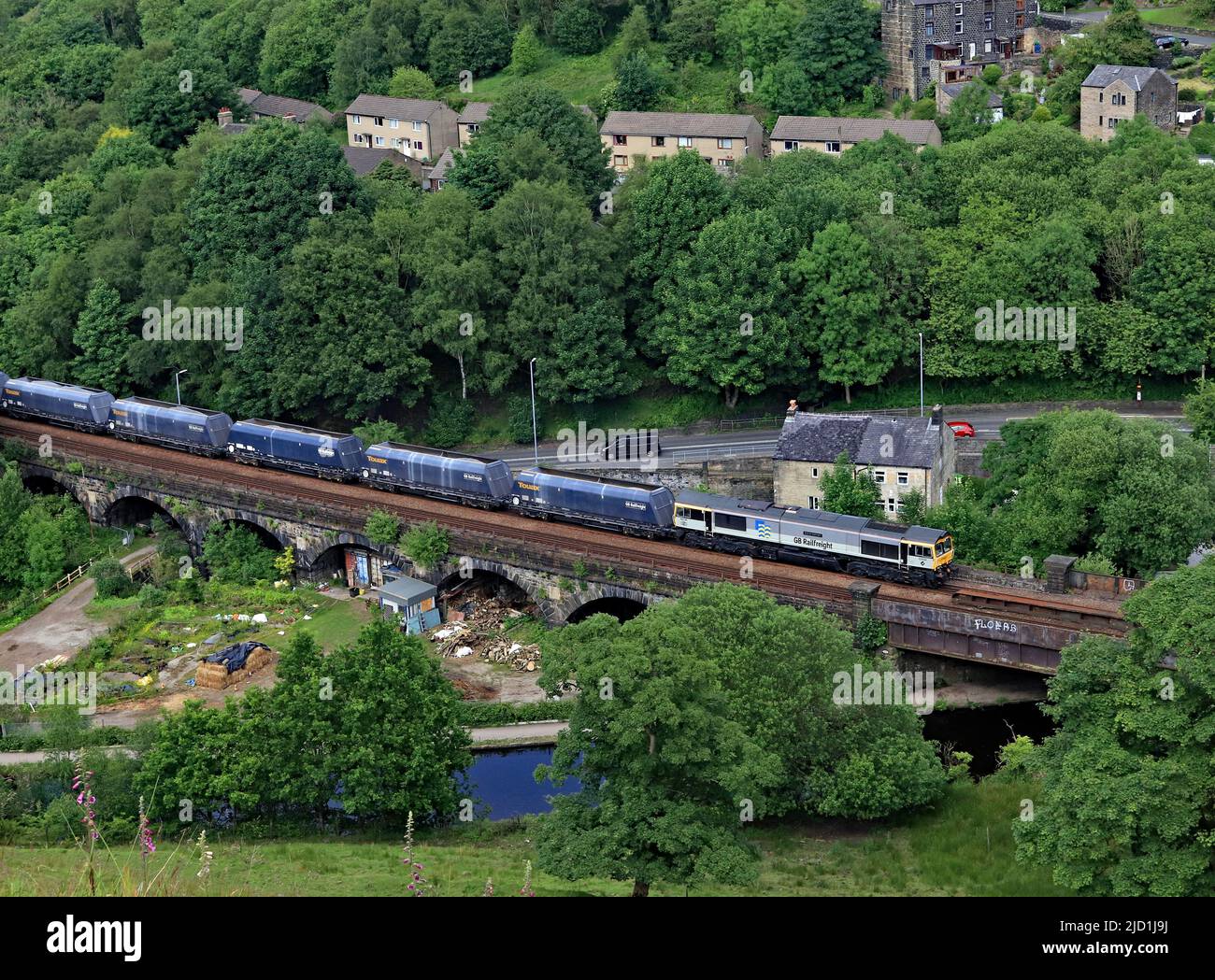 Die GBRF-Diesellokomotive 66794 wird den Rochdale-Kanal bei Todmorden im Calder-Tal mit einer Zuglast aus Stein in Richtung Manchester überqueren Stockfoto