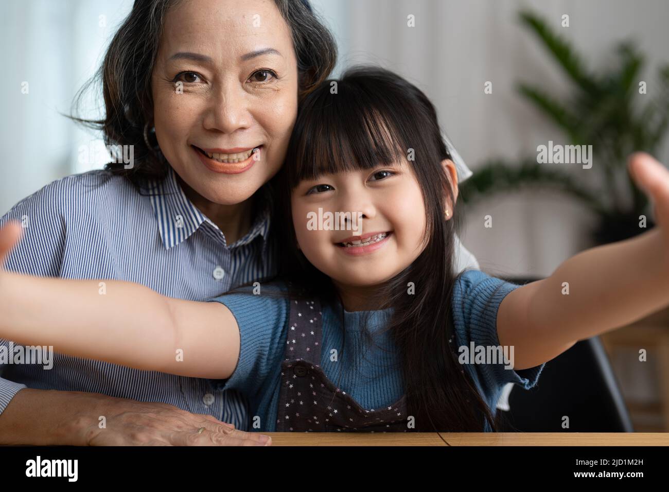 Nahaufnahme eines fröhlichen, glücklichen, älteren Großmutters, das Selfie mit ihrer entzückenden Enkelin macht. Sie blicken mit einem breiten Lächeln auf die Kamera Stockfoto