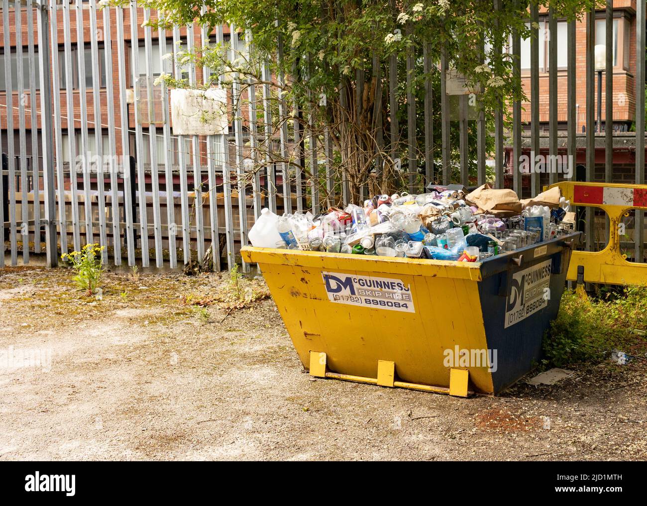 Ein gelber sprung voller Müll, der zur Abholung bereit ist Stockfoto