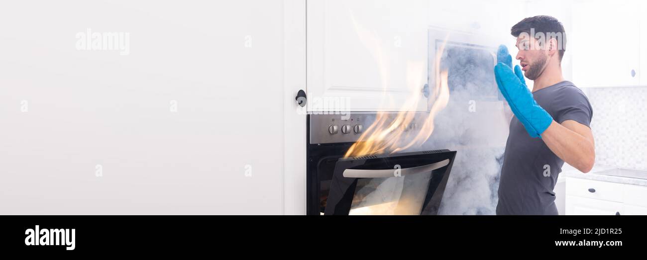 Angst junger Mann auf der Suche nach Feuer kommen aus dem Ofen in der Küche Stockfoto